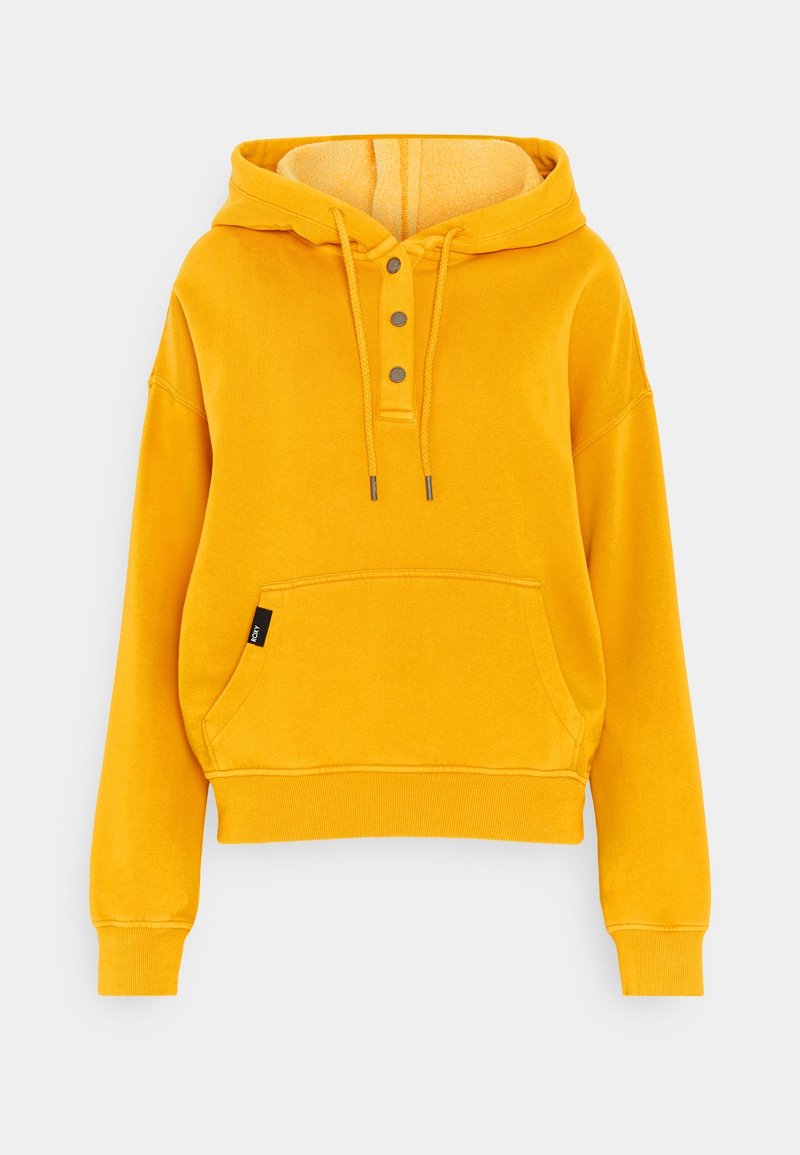 Sudadera amarilla con capucha y un interior acogedor, tres botones de metal en el escote y un bolsillo frontal con una pequeña etiqueta de la marca en el lateral.