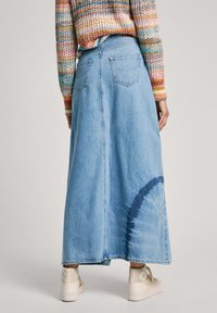 Denim maksi krilo v svetlo modri barvi z zadi�šnjim razporkom, ki ima dve zadnji žep in barvni krožni vzorec blizu roba.