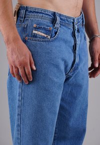 Hellblaue Jeans aus Denim mit geradem Schnitt. Ausgestattet mit kupferfarbenen Beschlägen, einer kleinen Vordertasche und einem Lederpatch am hinteren Bund.