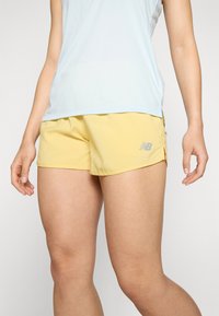 New Balance gula träningsshorts, lättviktsmaterial, shortsen har en åtsittande design med sidoflikar och en silverlogotyp på vänster ben.