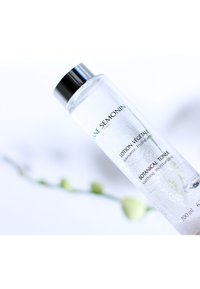 Heldere glazen fles met een metallic zilveren dop. Labels met zwarte tekst lezen "Lotion Végétale" en "Botanical Toner." Inhoud: 200 ml.