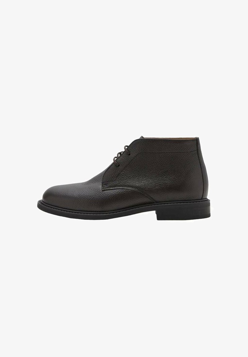 Bottine en cuir noir à la cheville avec lacets à l’avant, bout arrondi et petit talon superposé sur fond blanc.