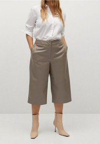 Culottes marrone chiaro in tessuto liscio, con tasche laterali, vita alta e vestibilità comoda, abbinati a stivaletti beige.