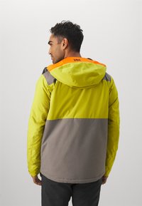 Chaleco de alta visibilidad con paneles en amarillo brillante y gris, detalles en naranja en la capucha y un tejido suave y ligero.