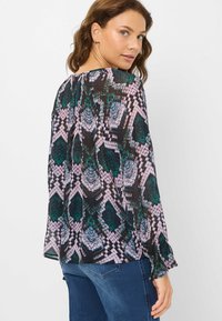 Langærmet bluse i gennemskinneligt stof med et sort, grønt og pink abstrakt mønster, afslappet pasform og rynket detalje på bagsiden.