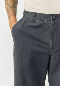 Kulgrå bukser lavet af let materiale. Har en knaplukning, sidelommer og en diskret tekstur med skræddersyet design.