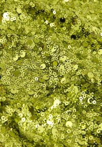 Grön paljett tyg, tätt täckt av glänsande cirkulära paljetter, som skapar en jämn, reflekterande yta med livlig färgvariation.