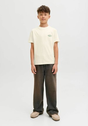 Lichtgele T-shirt met korte mouwen met groene tekst, gecombineerd met oversized donkerbruine broek en beige instapschoenen. Eenvoudig en casual ontwerp.