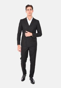 Completo nero doppiopetto con una vestibilità snella e sartoriale. Abbinato a una camicia bianca impeccabile e scarpe in pelle nera, che mette in mostra un aspetto elegante.