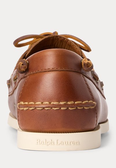 Brauner Leder-Mokassin mit genähten Details, einer Schleife oben und einer weißen Sohle mit „Ralph Lauren“ Prägung an der Ferse.