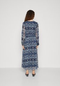 Rochie maxi dintr-un material transparent, de culoare albastră, cu un model floral. Dispune de mâneci lungi, talie strânsă și accente texturate. Silueta este fluidă și elegantă.