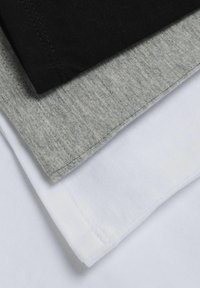 Tři naskládané trička v černé, šedé a bílé barvě. Tkanina vypadá hladce s viditelným švem na okrajích, což ukazuje na neformální design.