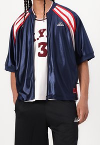 Námořnická saténová sportovní bunda s červenými a bílými pruhy, plný zip, krátké rukávy a logo Adidas na hrudi.