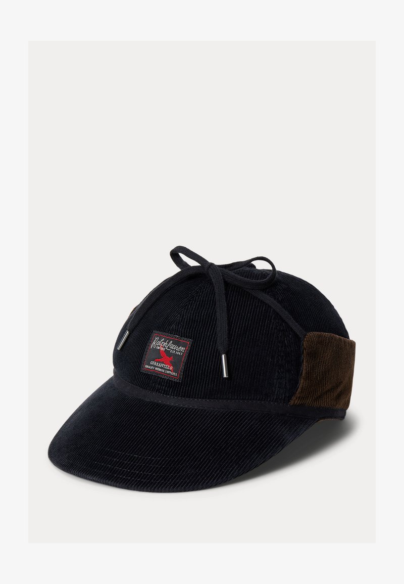 Svart keps i manchester med böjd skärm, dekorativ röd etikett och ljusbruna manchesterpaneler på sidorna. Har justerbar dragsko för passform.