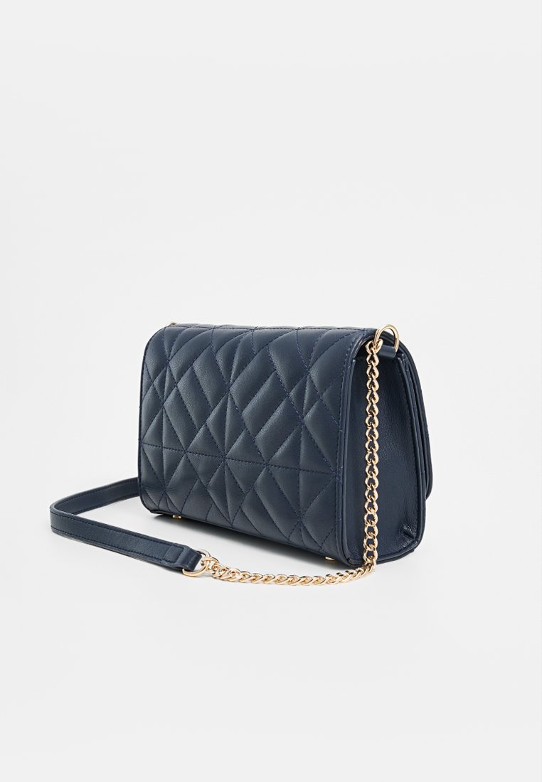 Bolso cruzado de cuero sintético acolchado en color marino con cadena dorada, de forma rectangular y con detalle en patrón de diamantes.