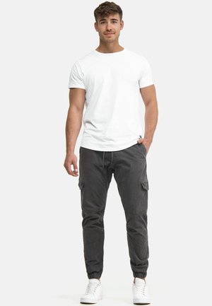 Vit t-shirt med korta ärmar kombinerad med grå cargo-byxor med elastiska muddar, flera fickor och dragsko i midjan, kompletterad med vita sneakers.