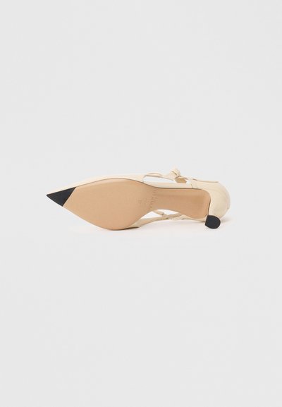 Μπεζ ψηλοτάκουνα παπούτσια με μυτερή μύτη, λεπτές φάσες στον αστράγαλο και μαύρη λεπτομέρεια στην άκρη. Λείος υλικό με σχεδίαση tapered heel.