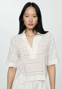 Witte, cropped shirt met een button-down kraag, uitgevoerd met open ruitpatronen en korte mouwen, gemaakt van lichtgewicht stof.