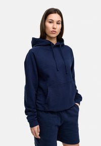 Navy blue hooded sweatshirt made from a soft fabric, featuring a front pocket, drawstring, and ribbed cuffs, paired with matching shorts.