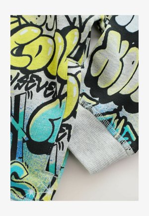 Pilkos ir juodos spalvos grafika su geltonais ir mėlynais akcentais. Textūriniu audiniu, su gumuotais rankogaliais ir siūlėmis.