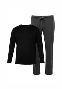 Chemise noire à manches longues avec un col henley et trois boutons, associée à un pantalon de jogging gris à cordon de serrage, offrant une coupe décontractée.