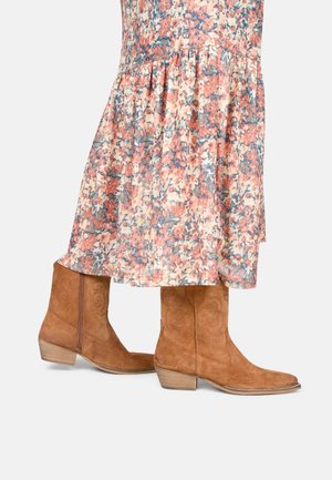 Stivali da cowboy in suede marrone con punta appuntita e tacco impilato, caratterizzati da accenti cuciti e una finitura leggermente testurizzata.