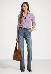 Camicia a righe a maniche lunghe bianca e viola, jeans a vita alta azzurri, borsa in pelle marrone e sandali aperti marroni.