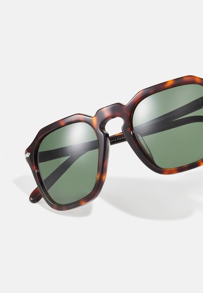Tortoiseshell sunglasses with green lenses, square shape, and thick frames, featuring a keyhole bridge design and sturdy black temple arms.