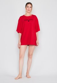 Czerwona, oversize t-shirt wykonana z miękkiego materiału, z nazwą marki "JOOP!JEANS" w czarnym tekście z przodu. Krótkie rękawy i luźny krój.