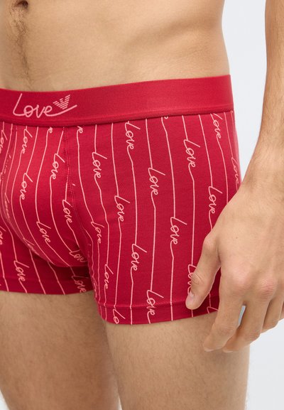 Crvene bokserice od mekanog pamuka s bijelim tekstom "love" u ponavljajućem uzorku, s čvrstim pojasom.