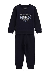 Navy-blaues Baumwoll-Sweatshirt und -Hose-Set mit gesticktem "GUESS"-Logo auf der Vorderseite. Gerippte Bündchen und Saum für eine figurbetonte Passform.
