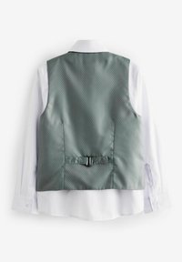 Gilet texturé gris avec un motif à pois subtil, orné d'une accent noir et d'une fermeture à l'arrière, porté sur une chemise blanche à boutons.
