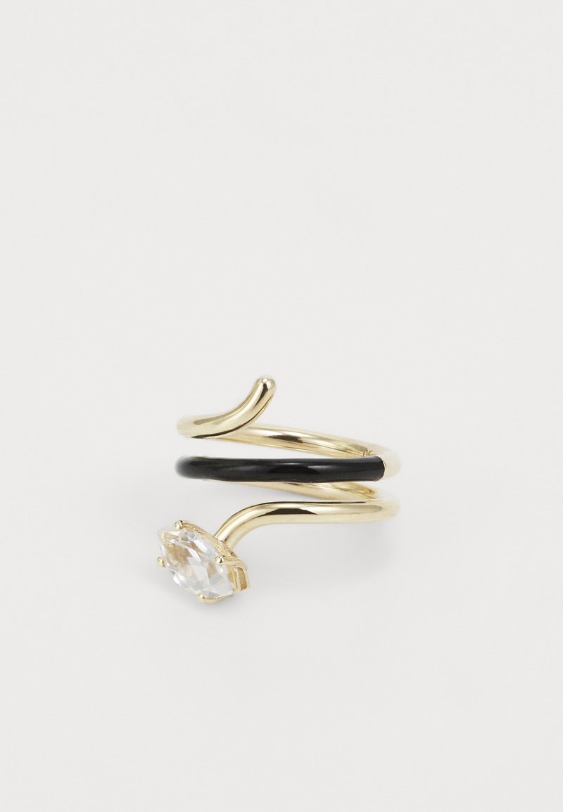 Zlatý prsten s prekrúteným dizajnom, čiernym pásikom a oválnym priehľadným kameňom osadeným v príchytke.