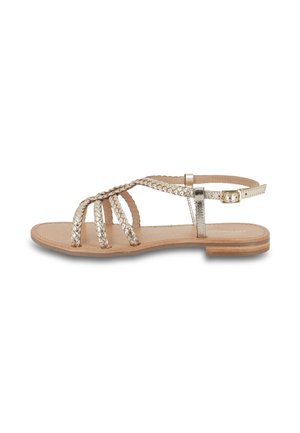 Sandales dorées métalliques avec des brides tressées, présentées avec une semelle plate et une bride de cheville ajustable. Design texturé sur les brides, base neutre.