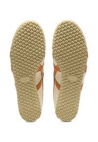 Tan and cream athletic shoes with a textured rubber sole. Features geometric patterns and a logo label on the side. Smooth leather upper.