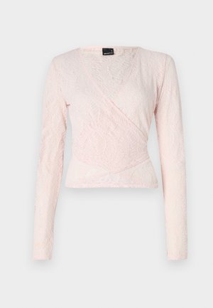 Rózsaszín csipkés, hosszú ujjú felső, kötött dizájnnal, amely texturált mintával és V-kivágással rendelkezik, kiemelve a testhezálló sziluettet.