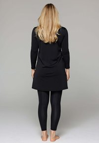 Zwarte tuniek met lange mouwen en een afgeronde zoom, gecombineerd met zwarte leggings. Glad stof met een aansluitende pasvorm, leggings tot aan de enkels.