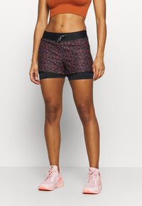 Svarta och blommiga mönstrade träningsshorts med elastisk midja, utrustade med dragsnodd och svart kant längs benen.