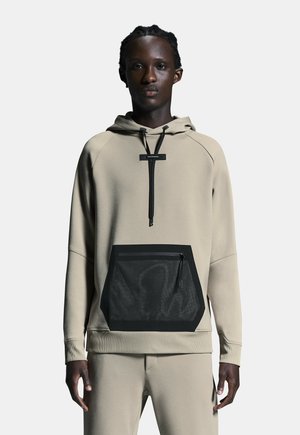 Beige huva sweatshirt med en svart nätficka fram, dragsko och ribbade muddar. Har en minimalistisk design och mjuk textur.