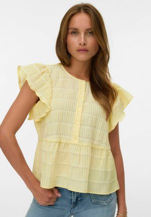 Haut jaune à manches courtes avec des bords volants et un tissu texturé. Présente un design à plusieurs niveaux et une patte de boutonnage à l'avant.