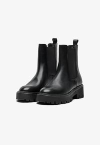 Black leather ankle boots with elastic side panels and pull tabs. Thick, ridged rubber soles provide traction. Smooth finish and rounded toe.