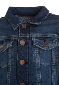 Džínová bunda v tmavě modré barvě s límcem, knoflíkovým zapínáním a dvěma náprsními kapsami s bronzovými detaily a viditelným šitím.