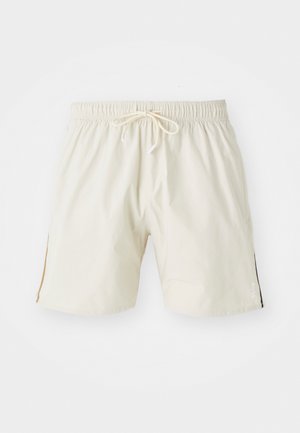 Krém színű fürdőnadrág, könnyű anyagból készült. Rugalmas derékpánttal és zsinórral rendelkezik, oldalt hasítékokkal. Márkájának logója az oldalon.