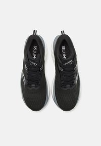 Scarpe da ginnastica nere con tomaia in mesh testurizzato, lacci piatti e suola bianca ammortizzata, con sottili dettagli di branding sulla linguetta.