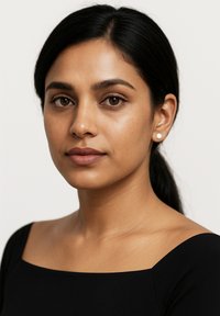 Svart off-shoulder topp, slät struktur, enkel halsringning. Modellen har mörkt hår och diskret smink. Naturligt ljus, neutral bakgrund.