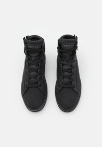 Černé tenisky s vysokou podrážkou, texturovaným síťovaným svrškem, zesílenou špičkou, plochými tkaničkami a nášivkou s logem na jazyku. Hladká gumová podrážka.