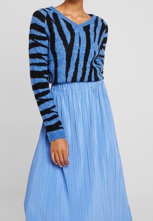 Maglione blu a maglia con strisce nere, design a V. Abbinato a una gonna plissettata blu chiaro. Il tessuto testurizzato aggiunge interesse visivo.