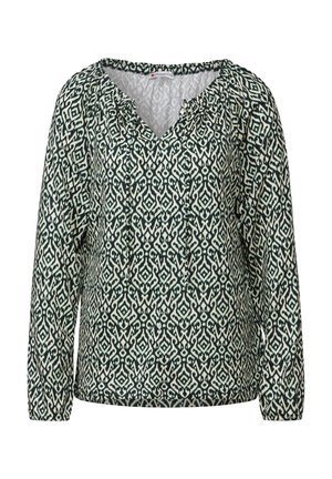 Chemise à manches longues avec un col en V, présentant un motif géométrique vert et blanc, un encolure froncée et une texture de tissu douce.