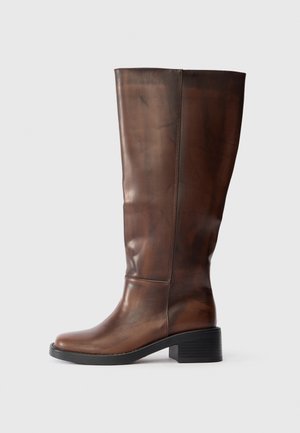 Barna bőr, térdig érő csizma, tömbsarkú és kerek orrú, sima felülettel és varrással, fehér háttér előtt.