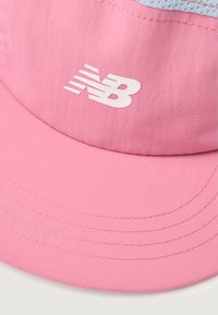 Gorra rosa hecha de un tejido suave que presenta un logo blanco de New Balance. Tiene detalles bordados y un borde redondeado, ligeramente curvado.